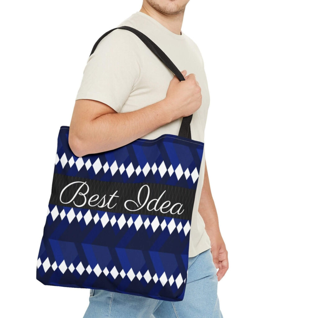 A man displays a blue and white tote bag with the text "best idea" written across it, showcasing a casual yet stylish look.