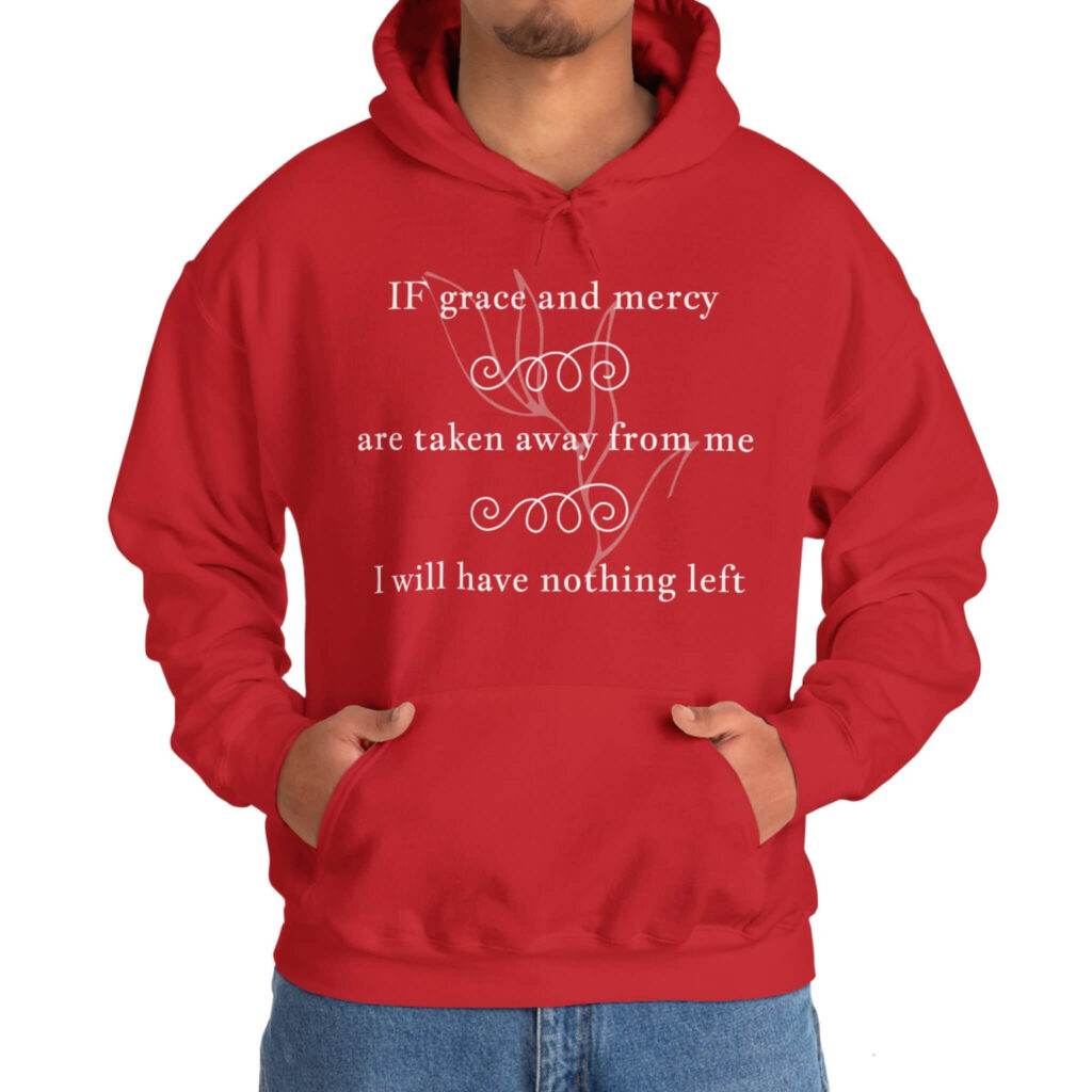 A man dressed in a red hoodie featuring the text, "grace and mercy shirt," promoting positivity and self-reflection.